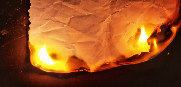 Wrinkled piece of paper going up in flames, with blank copy space.