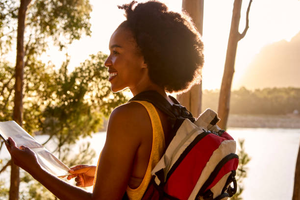 istock Woman With Map And Backpack On Vacation Hiking By Lake At Sunset 1473214028