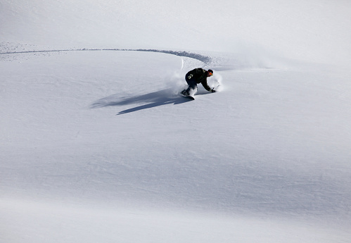 snow boarder cutting fresh tracks on new powder snow, New Zealand