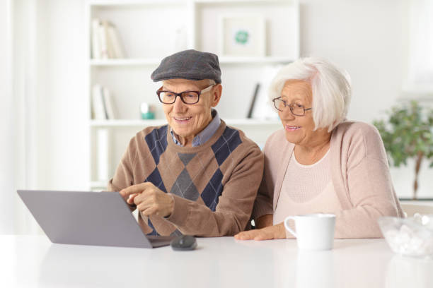 istock Happy elderly couple sitting at home in front of a computer 1473224619