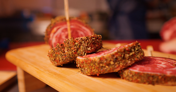 Close up of row beef roulade cuts with skewers on a wooden cutting board. Barbecue preps seasoned with pepper mix. Cooking conept.