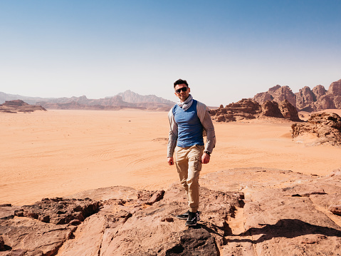 Stylish man and the sights of the Wadi Rum desert in Jordan. Clear, sunny day. Vacation and travel concept