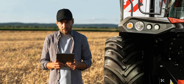 istock Farmer with digital tablet on a background of harvester. 1473233346