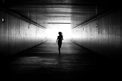 Black amd white image of girl running towards the light