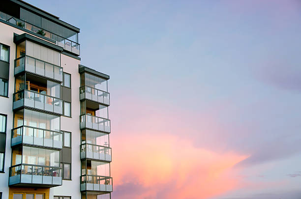 Sunset and modern architecture The sun is setting painting the clouds in vibrant colors. In the foreground modern architecture, a newly built housing high rise. apartment stock pictures, royalty-free photos & images