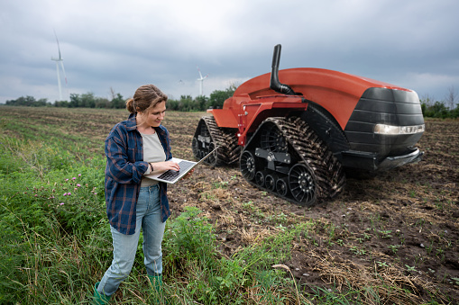 Farmer with digital tablet controls an autonomous tractor on a smart farm