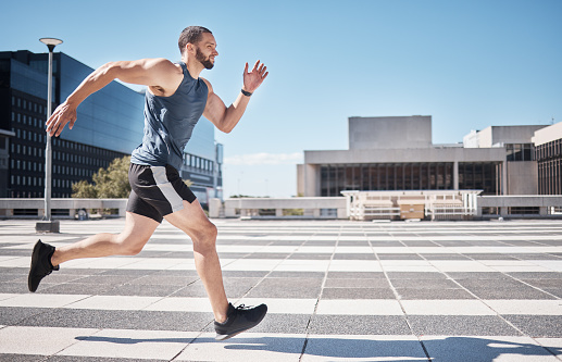 Fitness, exercise and man running in city for health and wellness. Sports runner, energy and male athlete exercising, cardio jog or training workout outdoors on street for race, marathon or endurance