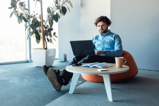 istock Business man using laptop sitting at desk in office 1473237403