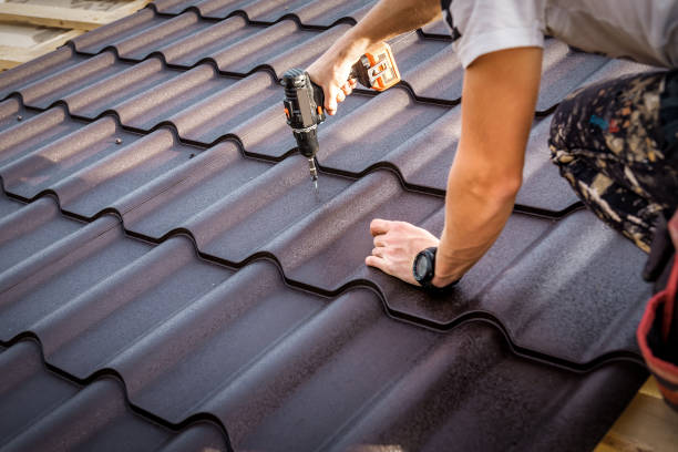 istock Professional master (roofer) with electric screwdriver covers repairs the roof 1473238086