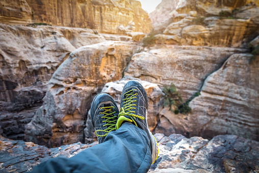 Legs in hiking shoes in red rocky mountains at sunset or sunrise