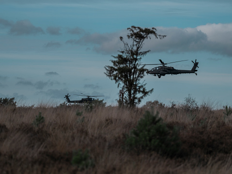 two apache helicopters low above the fields