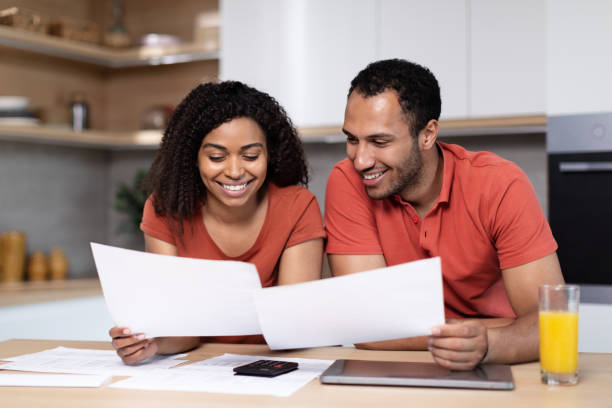 istock Happy young black couple with tablet pay bills and taxes, work with documents in kitchen interior 1473239783