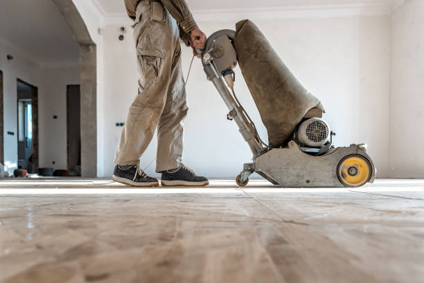 istock Professional carpenter grinding a wooden parquet floor by using floor sander in newly constructed house 1473239992