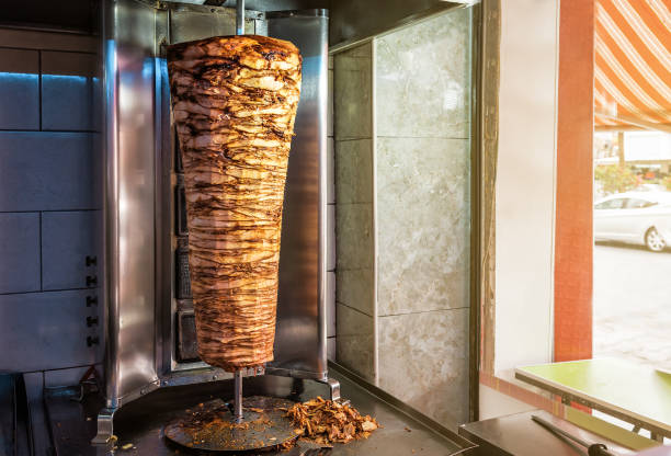 spiedo rotante per fare il tradizionale cibo di strada turco doner kebab sul tavolo in un negozio di street food - spit roasted barbecue grill barbecue pork foto e immagini stock