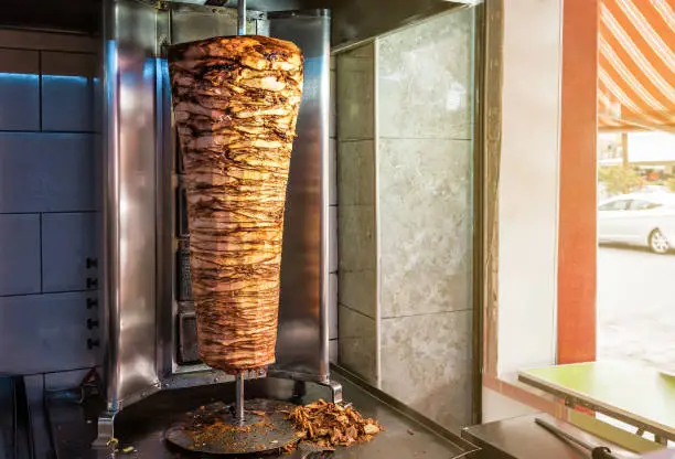 Rotating spit for making traditional turkish street food Doner Kebab on table in a street food shop. Food and drink theme