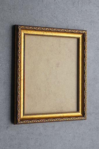 An ornate picture frame on a concrete wall.