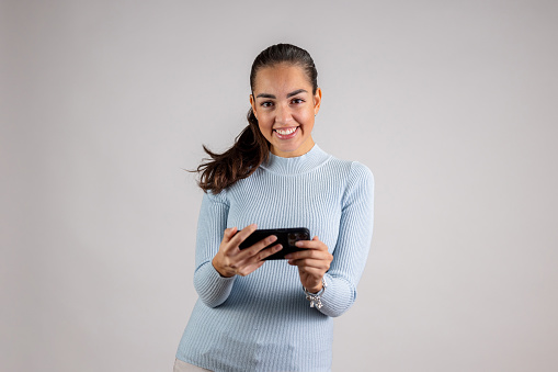 Hispanic Woman Holding Her Smart Phone,  Cheering And Laughing