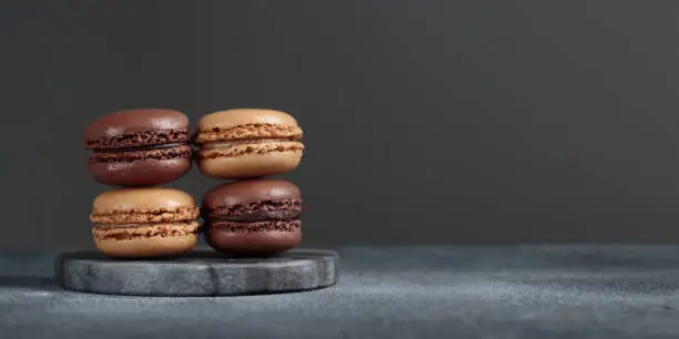 Chocolate eco handmade natural macaroons on dark background in the darkmood style. Horizontal banner top view with a copyspace