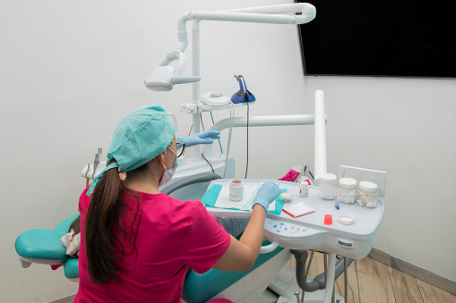 Woman dentist preparing her equipment to do a dental cleaning in her office