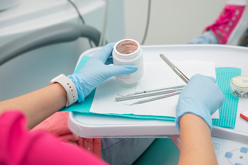 Dentist's hands taking paste for teeth cleaning