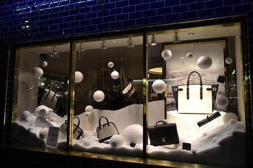 London, UK - November 27, 2013: Night view from the sidewalk of the pavedly enlightened interiors of the window set up of the high quality fashion bags \