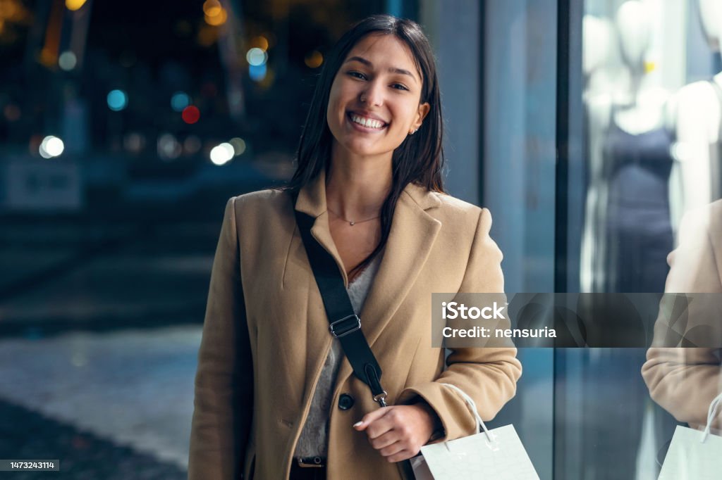 Pretty young woman looking at a shop window while walking in the street. Shot of pretty young woman looking at a shop window while walking in the street. 25-29 Years Stock Photo