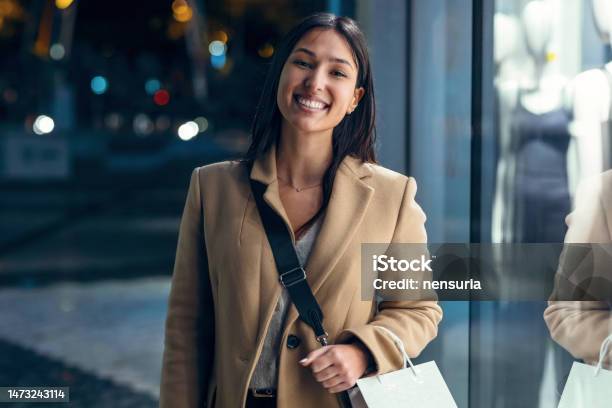 Pretty Young Woman Looking At A Shop Window While Walking In The Street Stock Photo - Download Image Now