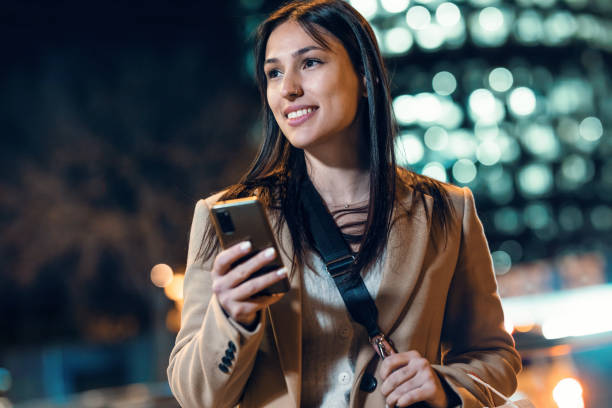 istock Beautiful young woman using her mobile phone at night. 1473243150
