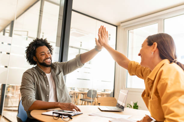 istock Two young happy diverse colleague sitting at desk and taking high five while working together in coworking space 1473244852