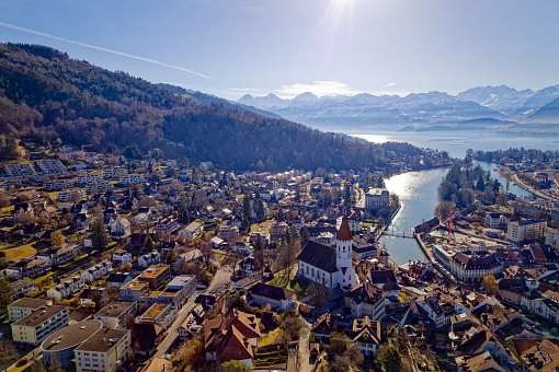 Aerial view of City of Thun with Aare River, Lake Thun an famous peaks Eiger, Monk and Virgin in the background on a sunny winter day. Photo taken February 21st, 2023, Thun, Switzerland.