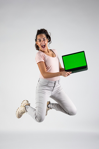 Confident and Happy Woman Holding A Laptop With Green Screen In The Studio