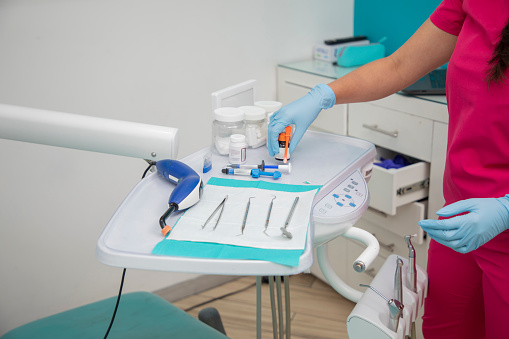 approaching the set of dental instruments, with the dentist's hands arranging the instruments