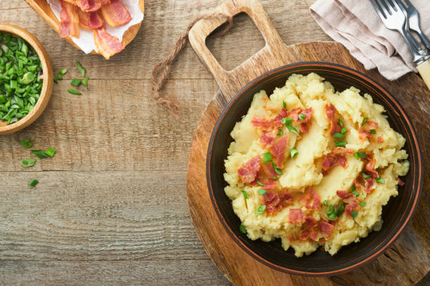 istock Mashed potatoes. Bacon mashed potatoes with green onion, pepper and cheddar cheese in bowl on old wooden backgrounds. Delicious creamy mashed potatoes. Top view. 1473249950