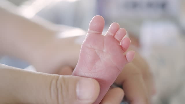 Mother hands holding and touching a little feet of baby newborn