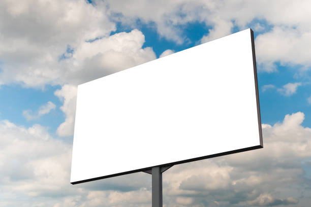 istock Mock up - blank white billboard against blue sky with white clouds 1473256144