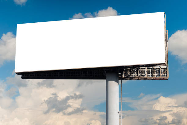 istock Blank wide white billboard against blue sky with white clouds - mock up 1473256469
