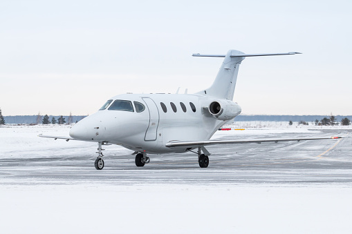 White private jet taxiing on airport taxiway in winter