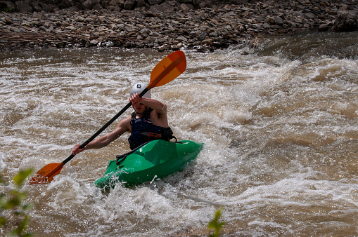 A front view of a woman kayaking and exploring mountain lake.