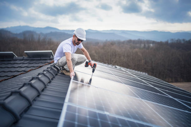 istock Solar panel installer installing solar panels on roof of modern house. 1473263958