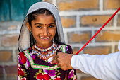 istock Doctor examines young Indian girl in desert village, India 1473264472