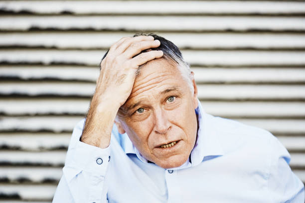 istock Handsome man looks stressed out as he clutches his head, with copy space on the roller door behind him 1473265385