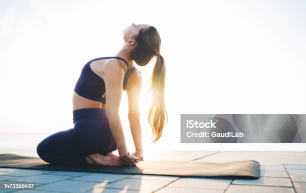 Sportswoman Stretching Body On Quay In Sunshine Stock Photo - Download Image Now - Yoga, Leggings, Outdoors