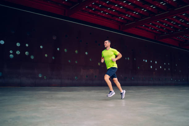 istock Side view of determined male runner sprinting during cardio training at urban setting, Caucasian man enjoying stamina exercising during warm up concentration on leisure for practice physical intensity 1473269720