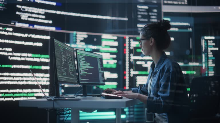 Portrait of Woman Working on Computer, Typing Lines of Code that Appear on Big Screens Surrounding her in a Monitoring Room. Female Programmer Creating Innovative Software Using AI Data and System