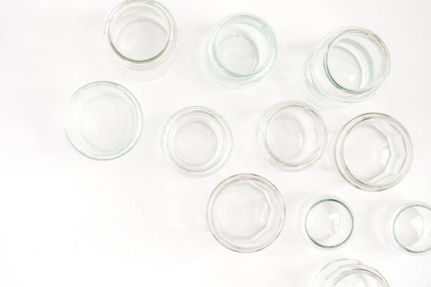 Variety of empty clear glass jars on wooden table against concrete wall