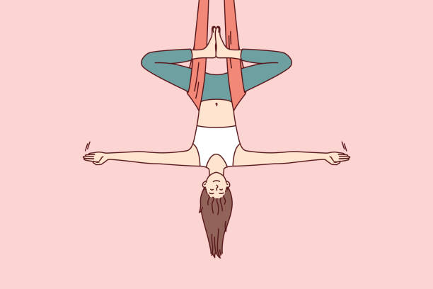 frau, die aerial yoga macht, hängt kopfüber in der hängematte und hält das gleichgewicht mit den armen an den seiten - antigravity yoga stock-grafiken, -clipart, -cartoons und -symbole