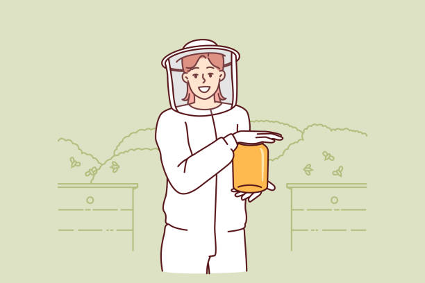 Young woman beekeeper in protective uniform holding jar honey standing in apiary among flying bees Young woman beekeeper in protective uniform holding jar of honey standing in apiary among flying bees. Girl farmer breeds bees in garden getting organic honey for sale at fair of ecological products woman beehive stock illustrations