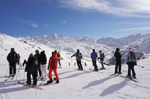 Les Menuires, France - 6 March 2023: A group of skiers are looking from Les Menuires up the valley towards the distant slopes of the Val Thorens section of the Three Valleys ski area.