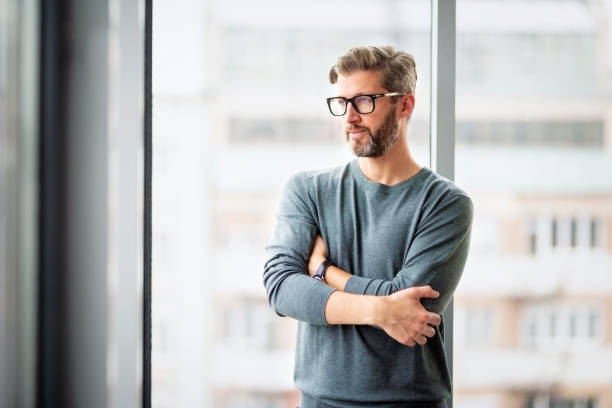 istock Confident businessman looking thoughtfully while standing with arms crossed in a modern office 1473274461