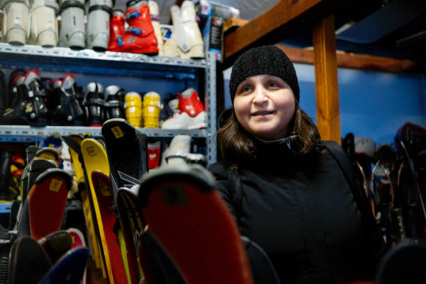 uma cliente alegre escolhe esquis em um depósito de aluguel de esqui e equipamentos de esqui. - skiing ski boot rental equipment - fotografias e filmes do acervo